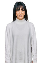 Young brunette woman with bangs wearing casual turtleneck sweater with a happy and cool smile on...