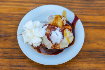 Close-up view of various flavors of ice cream topped with syrup on a restaurant table.