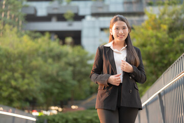 Professional young woman in a suit smiles confidently outside a modern office building - 775232386