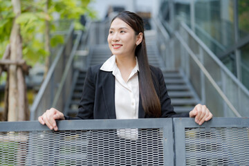 Young asian businesswoman smiling at the camera outside the office building
