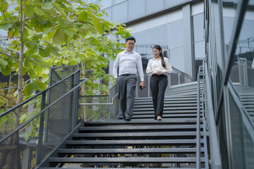 Business colleagues walking downstairs outdoors - 775233133