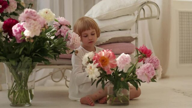 Caucasian child in white, holding pink and white flowers. Concept for family events, children's fashion and floristry.