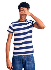 Young african american man wearing casual clothes peeking in shock covering face and eyes with hand, looking through fingers with embarrassed expression.