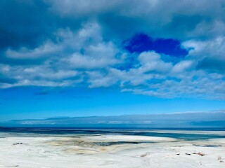 Frozen sea coast, ice at the sea, sea horizon, sky reflection on the water surface, natural colors