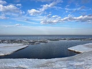 Frozen sea coast, ice at the sea, sea horizon, sky reflection on the water surface, natural colors
