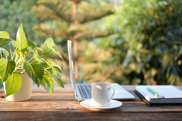 Laptop side view and coffee cup with notebooks on white table outdoor