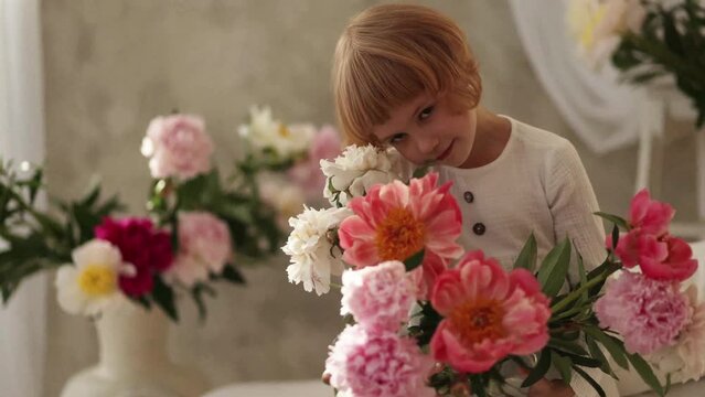 Caucasian child in white, holding pink and white flowers. Concept for family events, children's fashion and floristry.