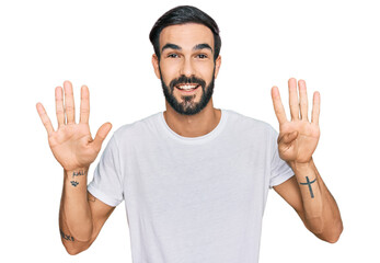 Naklejka premium Young hispanic man wearing casual white t shirt showing and pointing up with fingers number nine while smiling confident and happy.