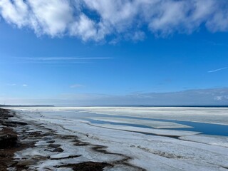 Frozen sea coast, ice at the sea, sea horizon, sky reflection on the water surface, natural colors