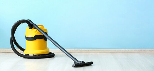 Modern vacuum cleaner near color wall