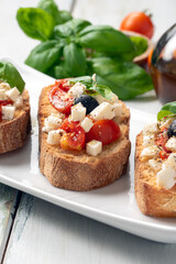 Piatto di bruschette condite con olio di oliva, pomodoro fresco, olive, basilico e origano, spuntino italiano, dieta mediterranea 