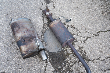 Broken exhaust and muffler of a car, rusted silencer fallen down on the road, breakdown of vehicle