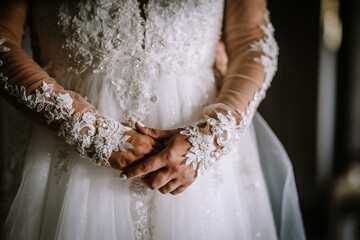 Valmiera, Latvia - Augist 13, 2023 - A bride's clasped hands are shown with detailed lace sleeves...