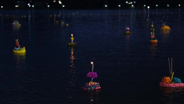 Decorated floats with lit candles and joss sticks in water during Loy Krathong festival celebration in Thailand