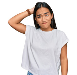 Young asian woman wearing casual white t shirt confuse and wonder about question. uncertain with doubt, thinking with hand on head. pensive concept.