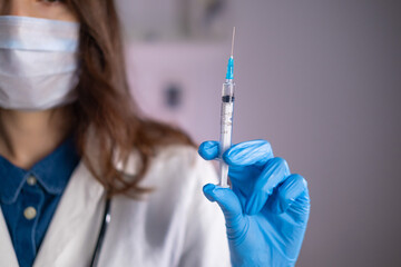 Close-up of a syringe with liquid in the hand of a doctor of a woman in a blue glove
