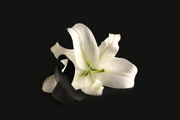 Beautiful lily flower with black funeral ribbon on dark background