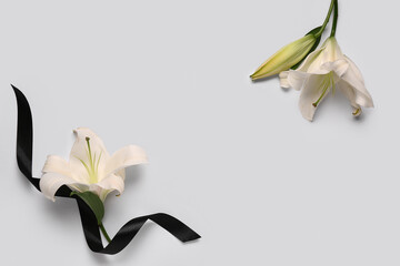 Frame made of beautiful lily flowers with black funeral ribbon on white background