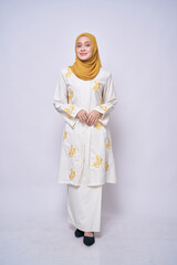 Full length portrait of Asian model wearing modern white batik kebaya with yellow hijab,  isolated over bright background. Stylish Muslim female fashion lifestyle  concept.
