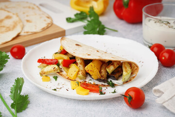 Plate of tasty pita bread with grilled vegetables on white background