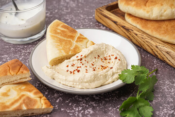 Plate of tasty pita bread with hummus on grey background