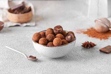 Bowl with tasty chocolate truffles on grey background