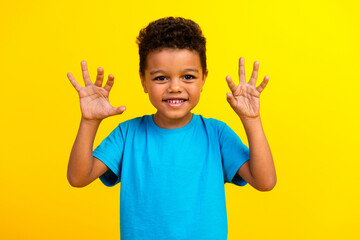 Portrait of funky small schoolboy with afro hair wear blue stylish t-shirt showing palms scare you isolated on vivid yellow background - obrazy, fototapety, plakaty