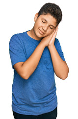 Teenager hispanic boy wearing casual clothes sleeping tired dreaming and posing with hands together while smiling with closed eyes.