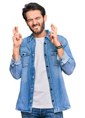 Young hispanic man wearing casual clothes gesturing finger crossed smiling with hope and eyes...