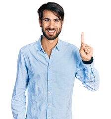 Hispanic man with blue eyes wearing business shirt pointing finger up with successful idea. exited...