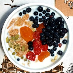 Breakfast: corn flakes, berries, candied fruits and seeds covered with milk in a plate. - 775267947