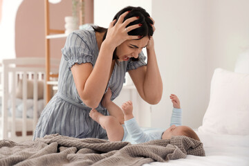 Angry young woman with her baby suffering from postnatal depression in bedroom