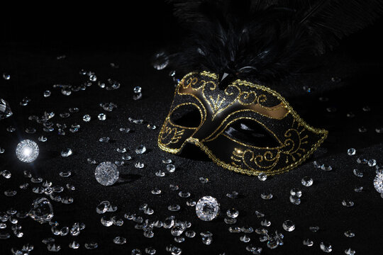 Masquerade gold mask with gemstones on black background.