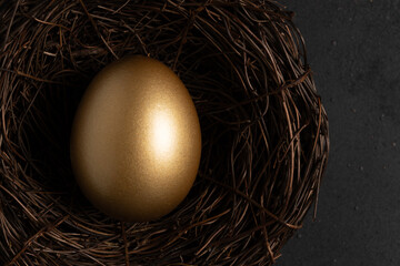 Close-up view of Golden egg in nest on a dark table. Easter concept.