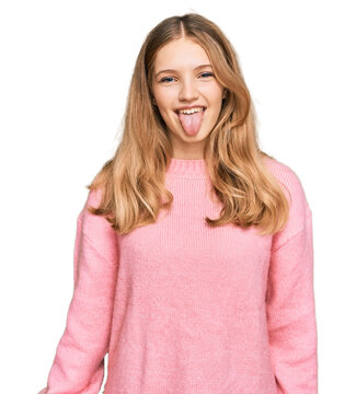 Beautiful young caucasian girl wearing casual winter sweater sticking tongue out happy with funny expression. emotion concept.