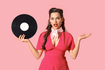 Portrait of surprised pin-up woman with vinyl disk on pink background