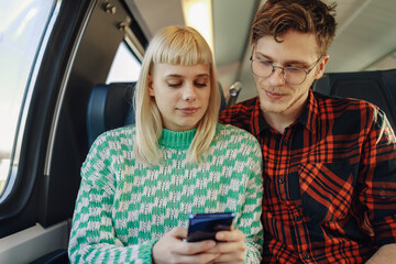 Portrait of a young travelers sitting in a train and using cellphone.