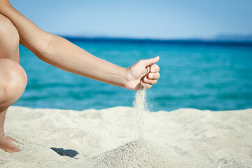 A hands pouring sand near the seashore on weekend nature travel