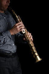 Naklejka premium soprano saxophone in hands on a black background