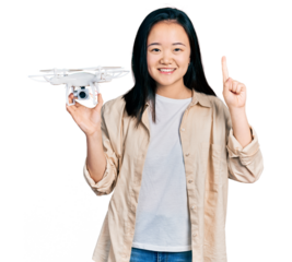 Young chinese woman holding drone smiling with an idea or question pointing finger with happy face, number one
