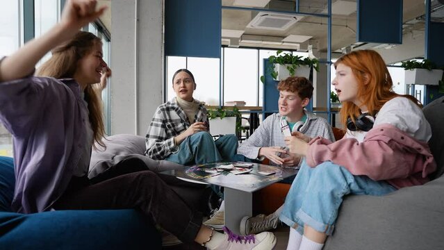 Group of happy teenagers friends playing board card games