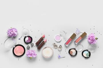 Fototapeta premium Eyeshadows palettes with lipsticks, earrings and flowers on white background