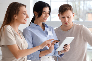 Real estate agent with young couple using tablet computer in new house