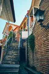 Low angle view of stairway leading to residential buildings with colorful wooden balconies in one of Tbilisi old town courtyards
