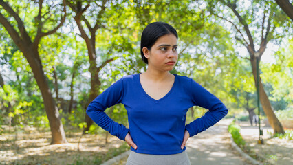 Tired young woman taking rest after doing physical exercise outdoors, fitness concept