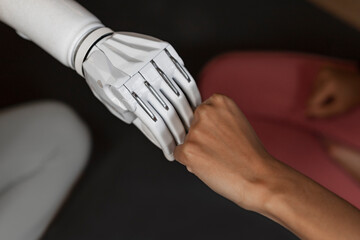 White male cyborg robotic hand pointing his finger to female human hand with stretched finger -...