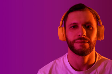 Young man in modern headphones on purple background