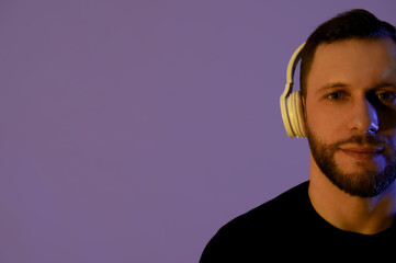 Young man in modern headphones on dark background
