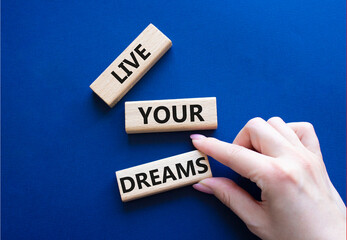 Live your Dreams symbol. Wooden blocks with words Live your Dreams. Beautiful deep blue background....