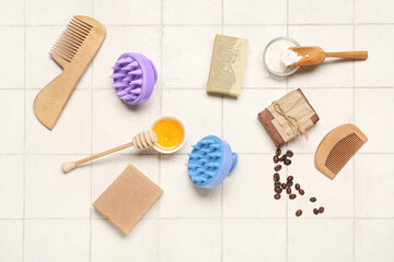 Fototapeta na wymiar Hair scalp massagers with shampoo bars, brushes and honey on white tile background